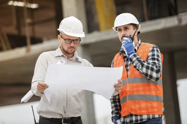 Engineers reviewing blueprints at a construction site